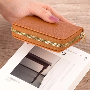 Close-up of brown litchi pattern leather card holder with secure gold zipper closure