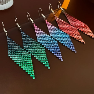 Détail macro de boucles d'oreilles à pompons losanges serties de diamants colorés