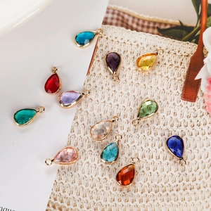 Close-up of teardrop glass birthstone charms with golden metal edges in assorted colors