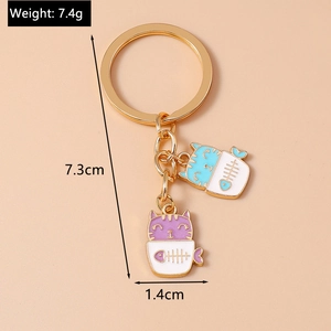 Detailed view of 7.4g cartoon cat keychains in white cups with blue and purple enamel