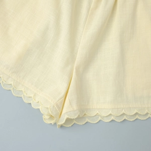 Détail macro de l'ourlet festonné sur un short beige respirant en mélange lin-coton