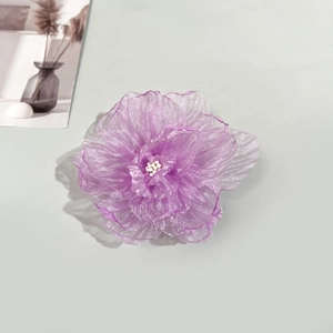 Détail d'une pince à cheveux camélia en organza violet avec pétales ondulés et perles