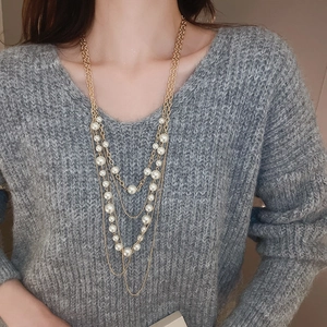 Close-up of elegant multi-layer long faux pearl necklace with delicate gold chains