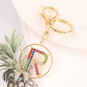 Close-up of gold letter R keychain featuring colorful rhinestones on a white plate