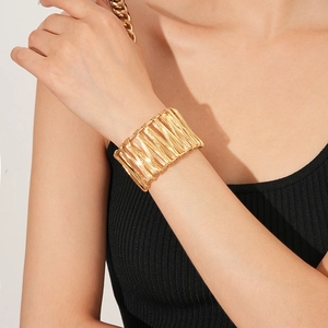 Vue détaillée d'un bracelet manchette large en fil doré enroulé sur un mannequin