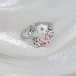 Detail of adjustable silver ring with pink enamel pig and star charms on silk