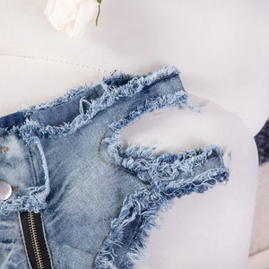 Nahaufnahme der blauen Denim-Hotpants mit ausgefransten Kanten und Reißverschluss-Details
