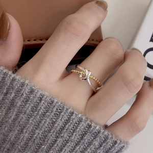 Detail of a two-tone knot ring in silver and gold plating worn on a model's finger