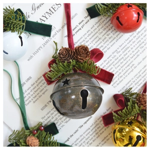 Close-up of vintage Christmas bells with pine cones and velvet bows on book background