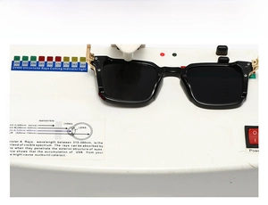 Testing UV400 protection on black square sunglasses with gold metal hinge detail