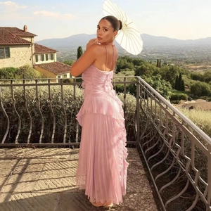 Elegant pink pleated maxi dress with ruffled details and open back for summer vacations