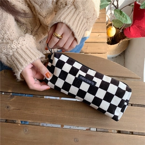 Close-up of black and white checkered corduroy pouch with zipper and brand label
