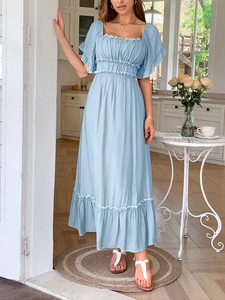 Femme en robe bleu clair à col carré et manches à volants dans une salle à manger