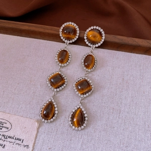 Detail of silver earrings featuring four brown cat-eye stones with zircon halo accents