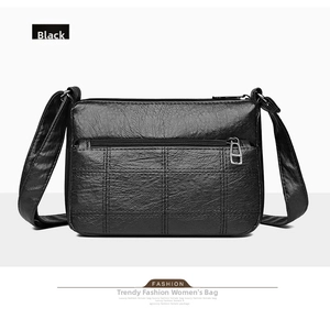 Close-up of black PU leather crossbody bag with quilted pattern and multiple zippers