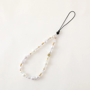 Bijou de téléphone élégant avec perles blanches et accents dorés de nœud sur un fond neutre