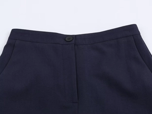 Detail of navy blue trousers showing waist button, hidden zipper, and twill fabric texture