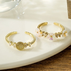 Adjustable 18K gold plated flower and zircon geometric rings set on a white plate