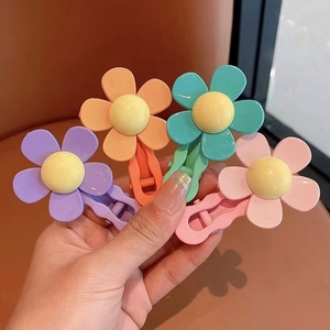 Detail showing four matte flower hair clips in purple, orange, cyan, and pink colors