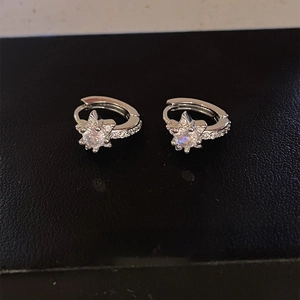 Minimalist silver star earrings with zircon inlay displayed on a black leather background