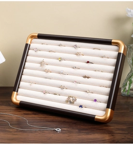 Macro view of walnut wood ring tray with beige velvet slots and gold metal corners