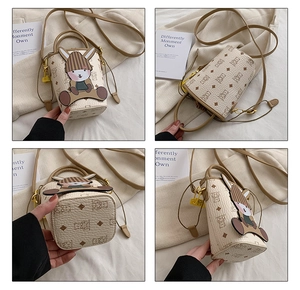 Detail view of mini bucket bag showing cartoon rabbit charm and bear monogram pattern