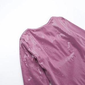 Detail shot of shimmering purple sequins on long sleeve dress fabric with metallic finish