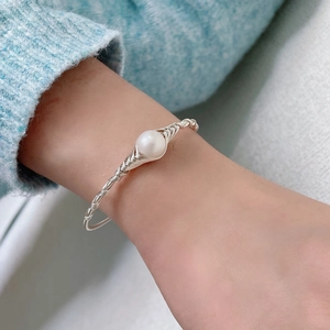 Elegant silver wire-wrapped bracelet with a white freshwater pearl on woman's wrist