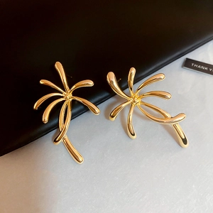 Detailed macro view of gold flower earrings with radial fireworks design on a premium background