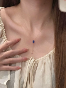 Détail d'un collier en or avec pendentif saphir bleu carré et pampilles en diamant sur mannequin