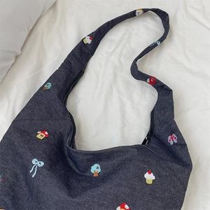 Detail of embroidered mushroom and cupcake patches on dark blue denim tote bag