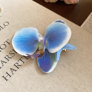 Detailed macro view of a blue orchid and acrylic starfish hair clip on linen background