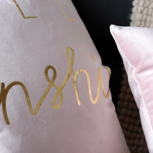 Detail showing pink velvet pillowcase texture with golden sunshine letter embroidery