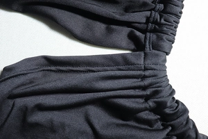 Detailed view of the black ruched dress fabric with precise stitching and cutout design