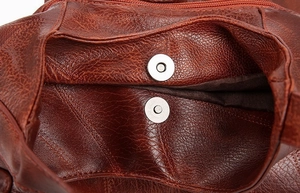 Detail view of the brown leather tote bag showing magnetic buckle and secure zip closure