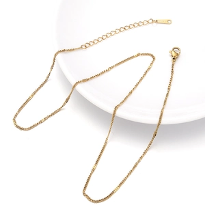 Gold stainless steel sequin chain necklace with lobster clasp on white ceramic plate
