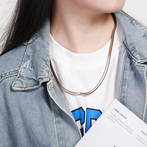 Detailed view of a gold flat snake chain necklace worn by a model in casual attire