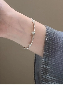 Dettaglio del bracciale in argento con ciondolo a farfalla su un polso femminile