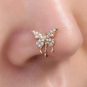 Macro close-up of a gold butterfly nose cuff with clear crystals on a female model