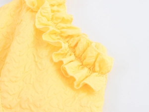 Close-up of yellow embossed bubble textured fabric with ruffled sleeve detailing
