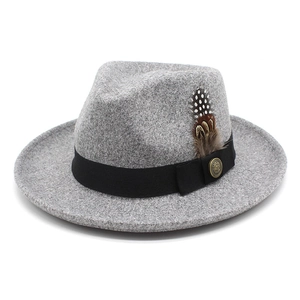 Detail of grey fedora with black grosgrain band, gold emblem, and spotted feather accent