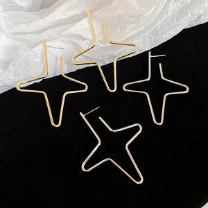 Detail view of large geometric star-shaped hoop earrings in gold and silver finish