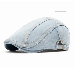Detail of light blue denim ivy cap with yellow stitching and adjustable metal side buckle