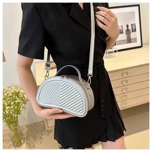 Borsa a mezzaluna argento trapuntata con cuciture a V indossata su blazer nero