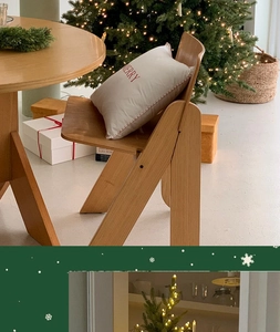 Detailed view of solid wood table and chair with festive Merry embroidered pillow