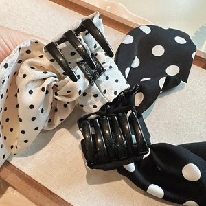 Close-up of polka dot ribbon bow hair claws in black and beige on a wooden tray
