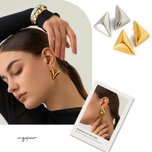 Dettaglio di orecchini a lobo triangolari geometrici in finiture oro e argento lucido