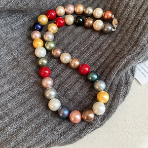 Detailed shot of multi-colored pearl necklace with silver clasp on grey fabric