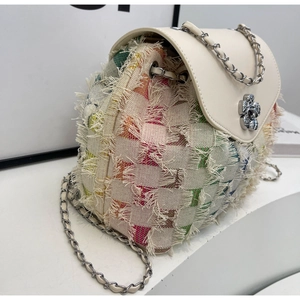 Detail view of denim fringe texture and silver flower clasp on women chain backpack