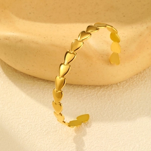 Detailed macro view of 18K gold-plated knotted heart pattern on minimalist open C-shaped cuff